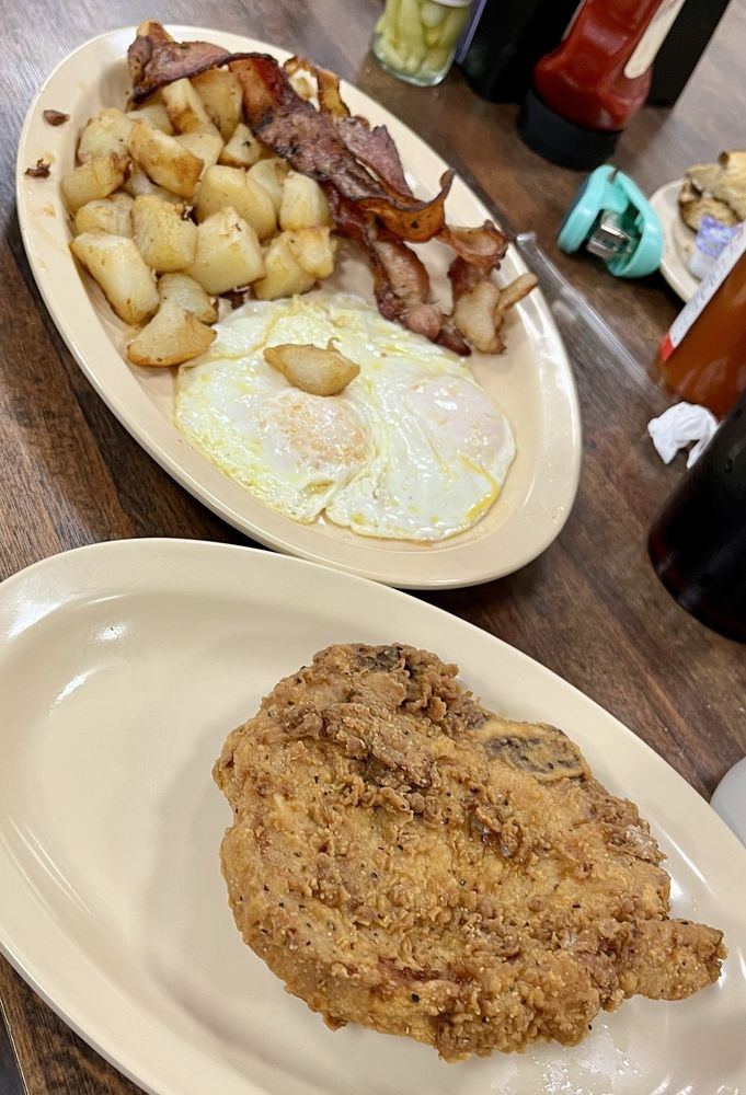 Fried pork chop breakfast with eggs over easy and home fries